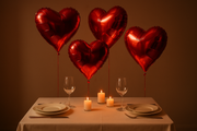 Red heart shape foil balloons floating over a table set for 2